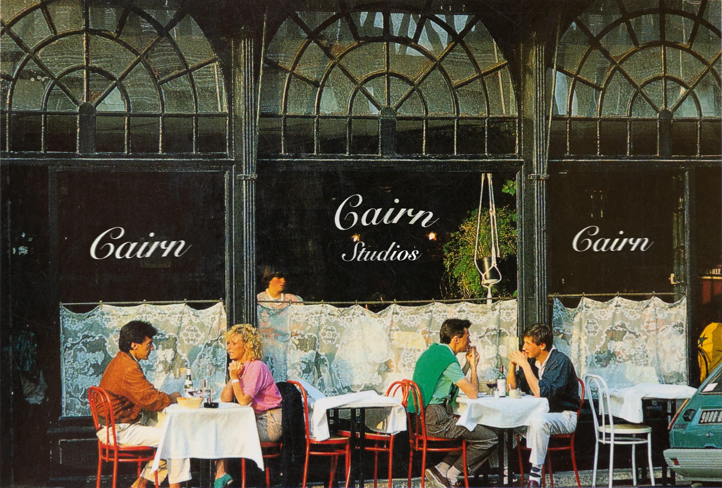 A sidewalk cafe with Cairn Studios lettered on its windows